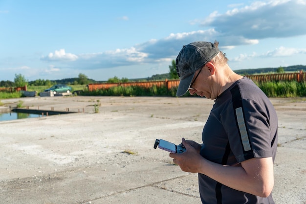The pilot of an unmanned aerial vehicle holds a drone control panel in his hands Flying a quadrocopter over an old abandoned quarry A blogger launches a drone while traveling