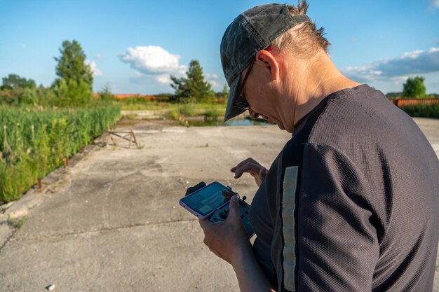 The pilot of an unmanned aerial vehicle holds a drone control panel in his hands Flying a quadrocopter over an old abandoned quarry A blogger launches a drone while traveling