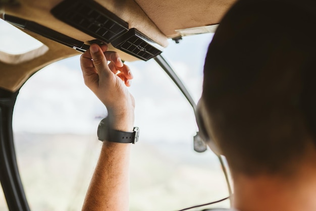 Pilot with headset initiating controls in private helicopter. Helicopter pilot sitting in the cockpit. Latin man.