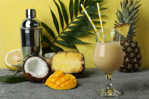 Pina colada cocktail and ingredients against yellow textured background.