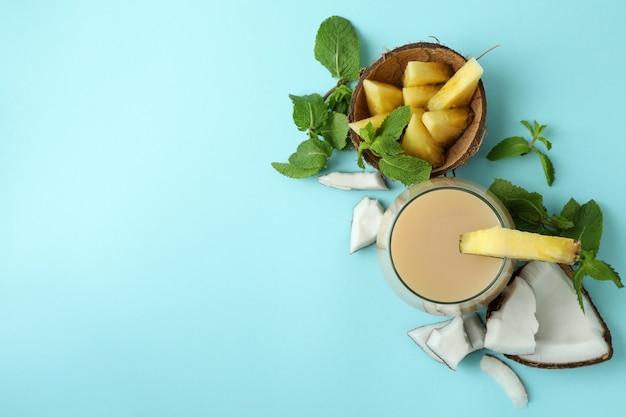 Pina colada cocktail and ingredients on blue background.