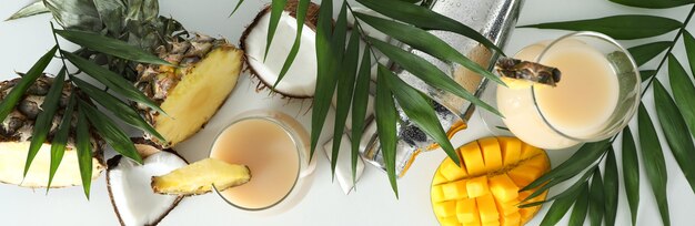 Pina colada cocktail e ingredienti su sfondo bianco.