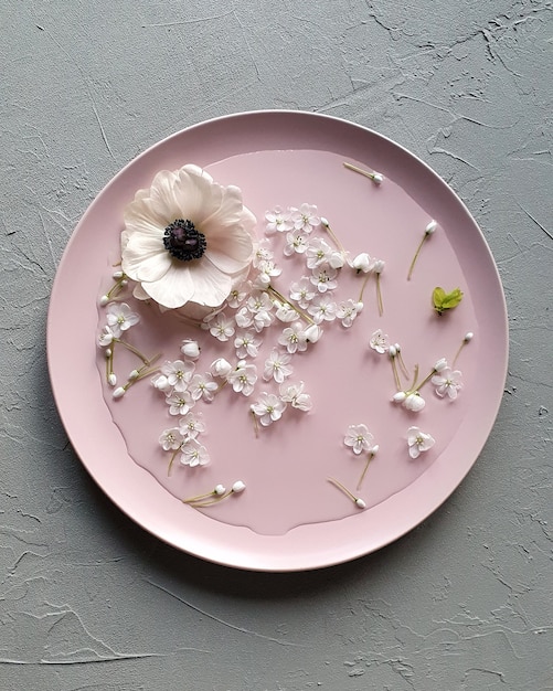 写真 灰色のテーブルにアネモネの花とネギの花とピンチプレート。上面図、フラットレイスタイル。