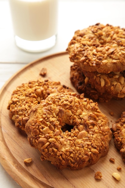 Pinda cookies op snijplank met melk op witte houten achtergrond. Verticale foto.