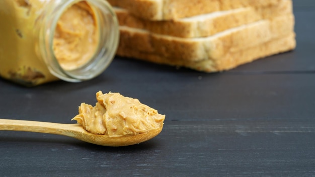 Foto pindakaas en volkorenbrood op een zwarte houten tafel