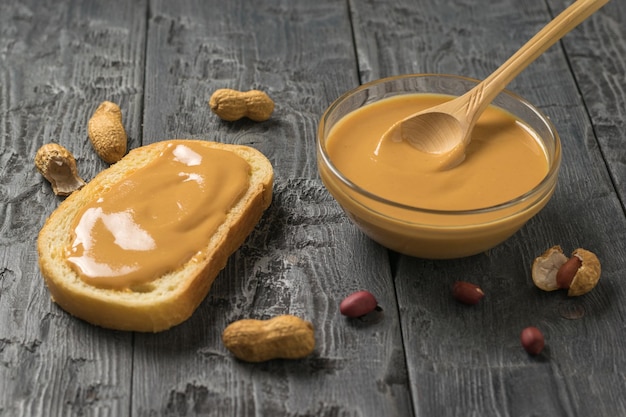 Foto pindapasta in een kom en op een stuk brood op een houten tafel