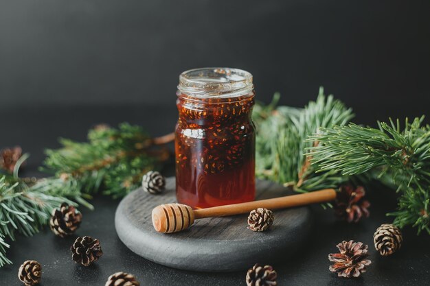 Pine cone jam in a glass jar against the background of pine branches and cones