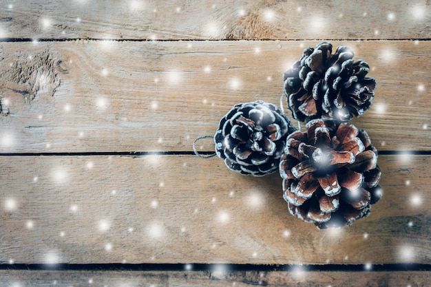 Pine cone and white snow on wood table background with space.