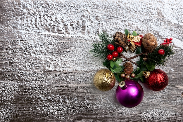 Pine Cone with a bell and colorful Christmas ball on snowy wooden background. Christmas decoration