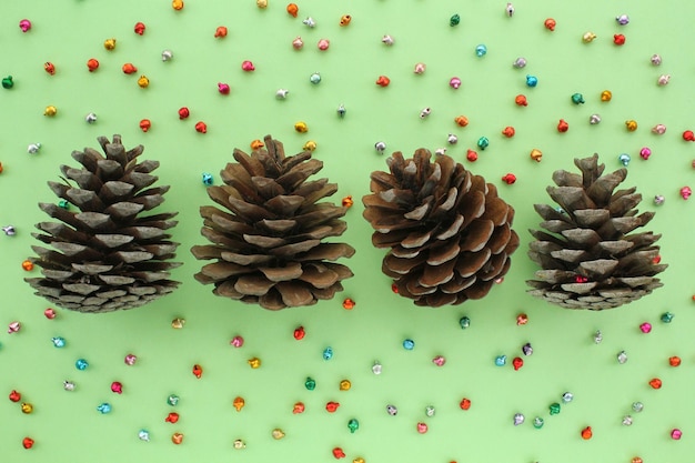 Pine fir cones of coniferous tree and jingle bells isolated on green background. Creative christmas