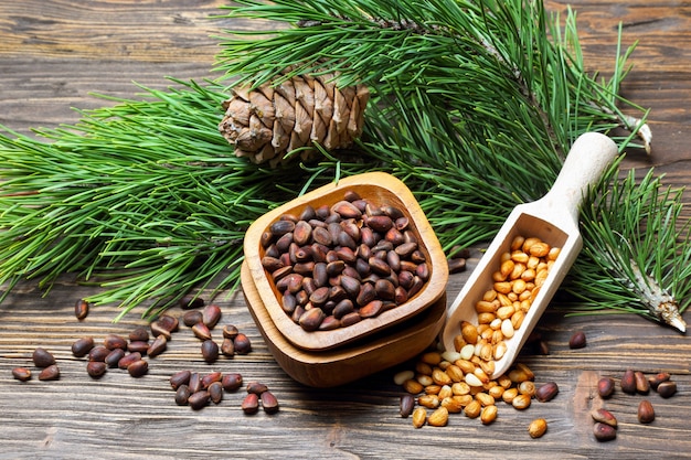 Pine nuts in a bowl and pine cone on a wooden table