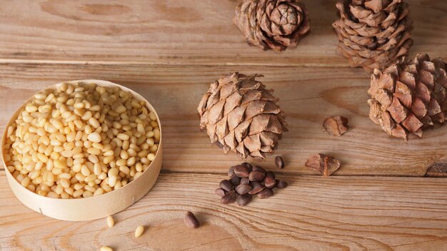 Pine nuts and cedar cones are on a wooden table.