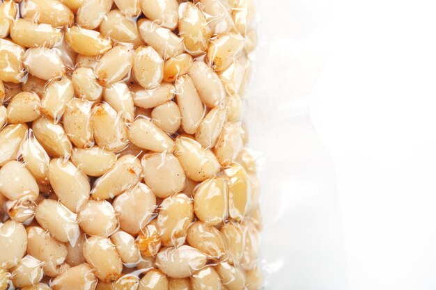 Pine nuts in a transparent vacuum package over a white background