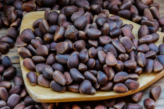 Pine nuts in the wooden spoon on a wooden board background. Pine nuts.