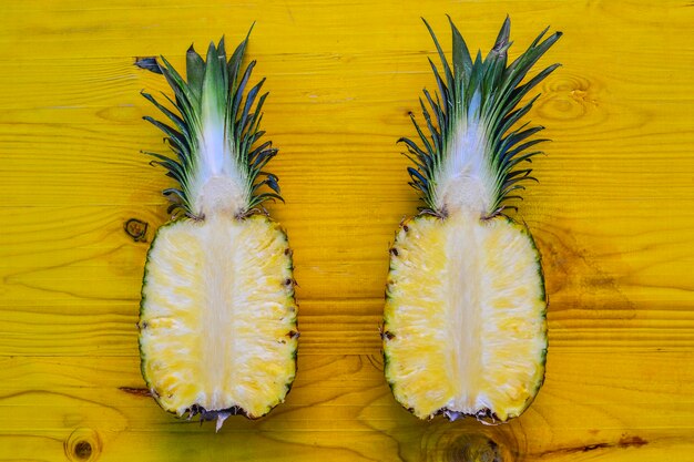 Pineapple ananas isolated on yellow table. Top view