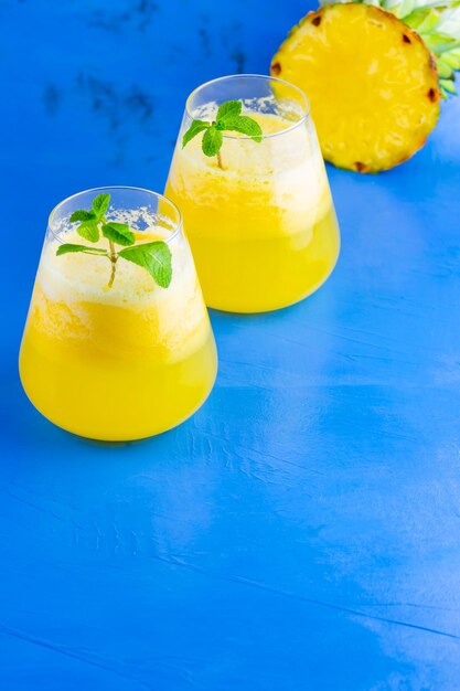 Photo pineapple cocktail on a blue background cold pineapple cocktail with mint summer tropical cocktail