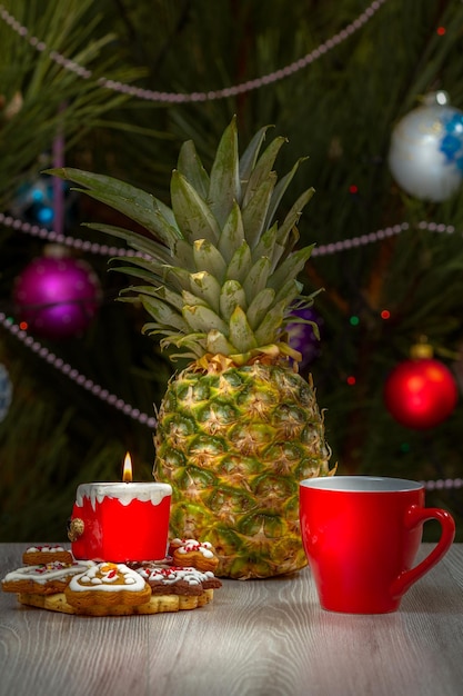 Pineapple cup of coffee and a fir tree with Christmas ornaments on the background