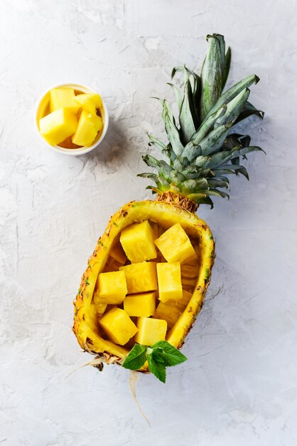 Pineapple cut into pieces on a gray table.