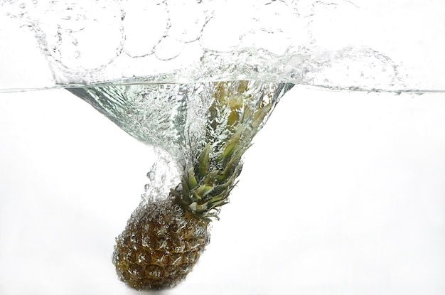 Photo pineapple falls in water.  fruit in water. aqua shooting.  food. big pineapple in the water. spray f