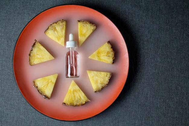 Pineapple flavored vape liquid lies with pineapple pieces on a plate