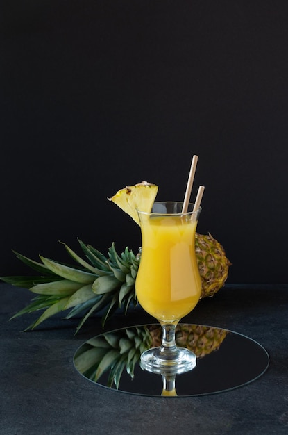 Pineapple fresh juice in glass on black background