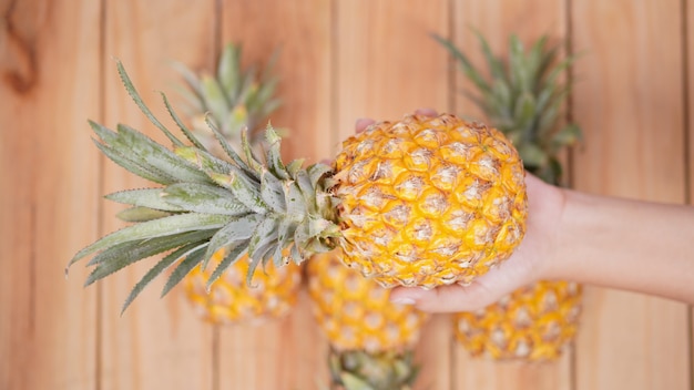 Frutta dell'ananas nel palmo su un fondo di legno