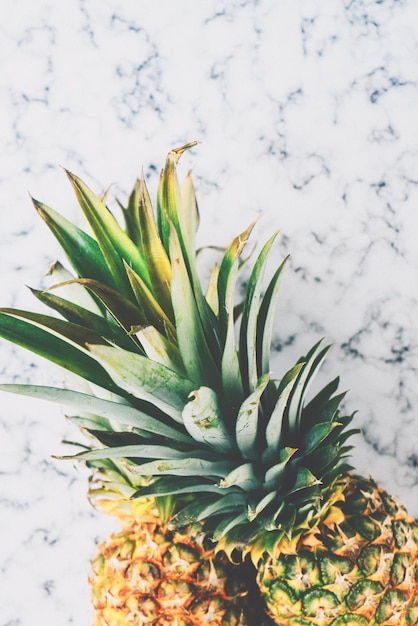 A pineapple is sitting on a marble counter top.