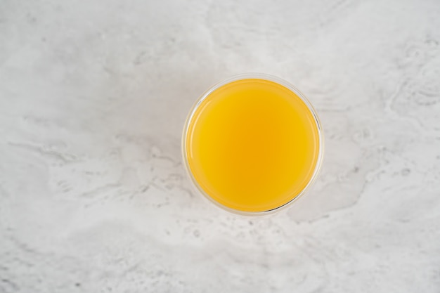 Pineapple juice in double glass cup on white stone table close-up. Isolated