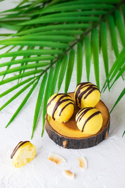 Pineapple and mango sweets in yellow chocolate on a wooden cut sugar gluten and lactose free