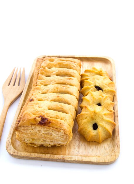 Pineapple pie and cookies in wooden plate on white background