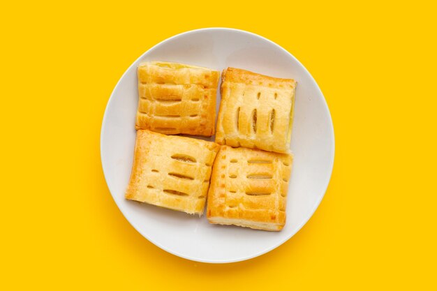 Pineapple pie in white plate on yellow background.