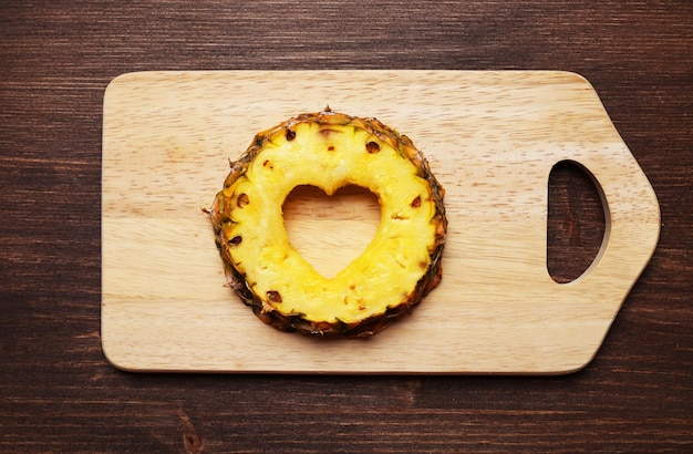 Pineapple slice with cut in shape of heart on wooden background