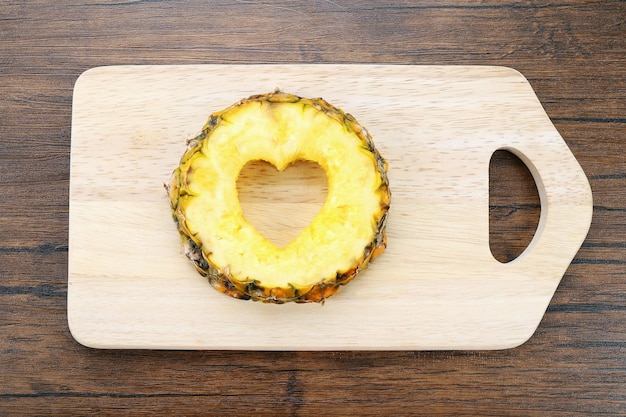 Photo pineapple slice with cut in shape of heart on wooden background