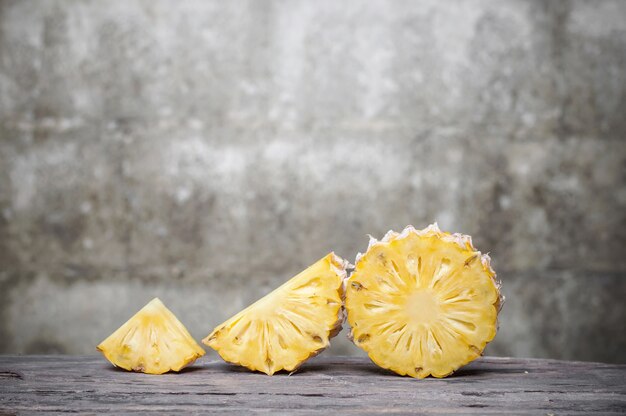 Foto fetta di ananas sulla tavola di legno con il vecchio fondo del muro di mattoni