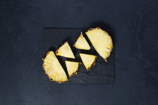 Pineapple slices on black stone Board with space for text