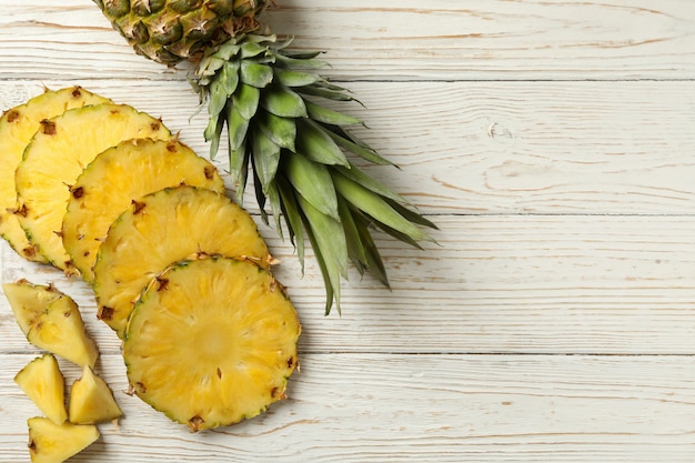 Pineapple and slices on white wooden background