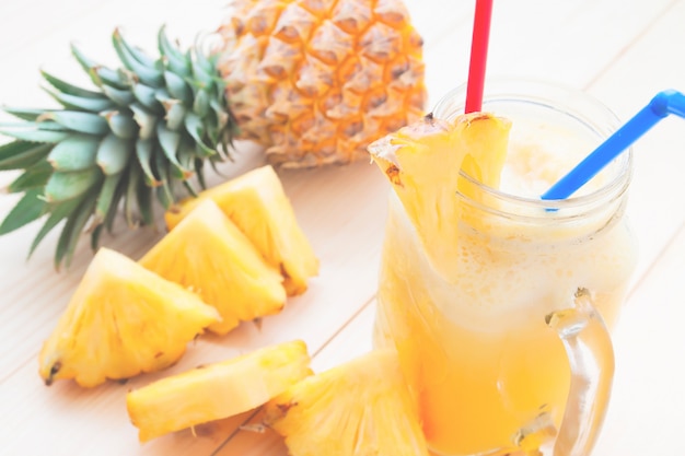 Pineapple smoothie and fresh pineapple slice on wooden table