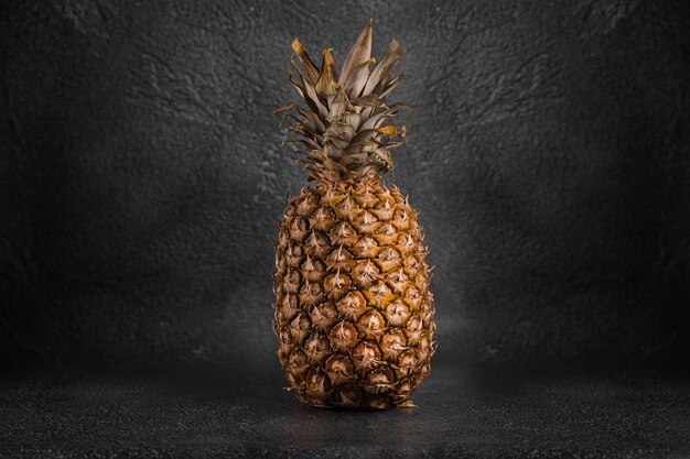 Pineapple tropical fruit on dark stone table.