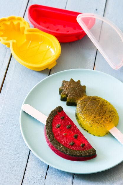 Pineapple and watermelon popsicles on blue wooden table