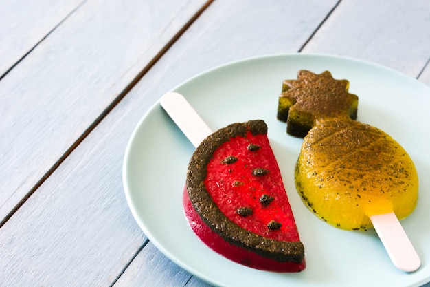 Pineapple and watermelon popsicles on blue wooden table