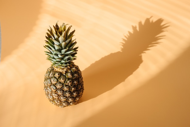 Pineapple with hard trendy shadow on pastel yellow background.