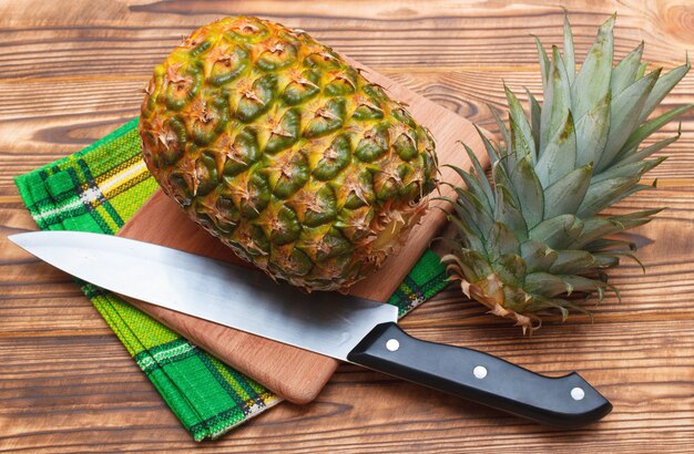 Foto ananas con la cima affettata su fondo di legno