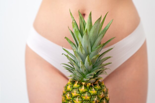 Pineapple on woman's body in white panties.