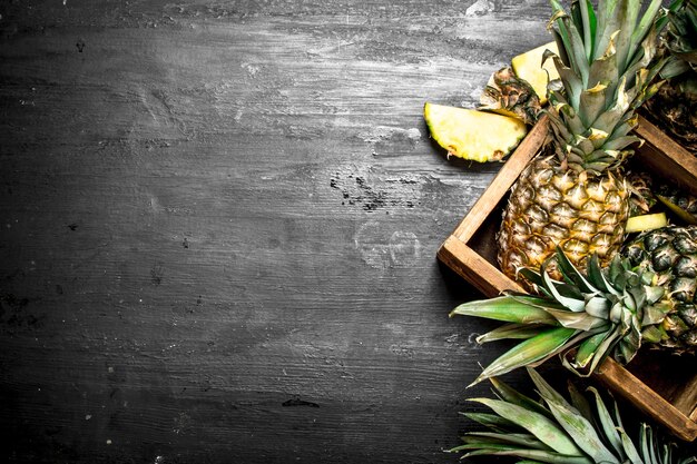 Pineapples in an old box on black chalkboard