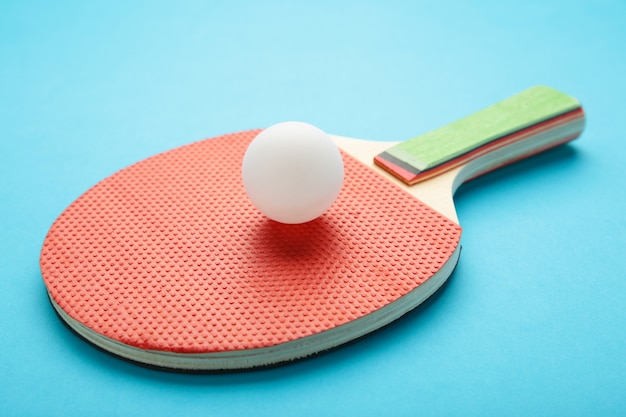 Ping pong paddle with ball on blue