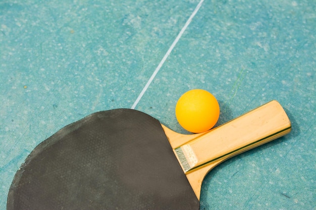 Ping pong paddles and ball on retro blue wooden background Rackets ruined by time