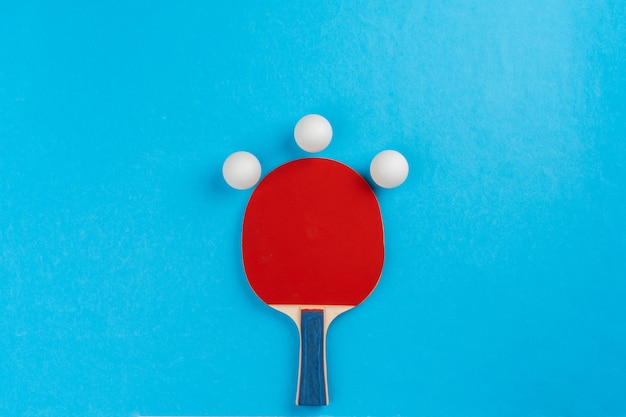 Ping pong racket and ball on blue surface
