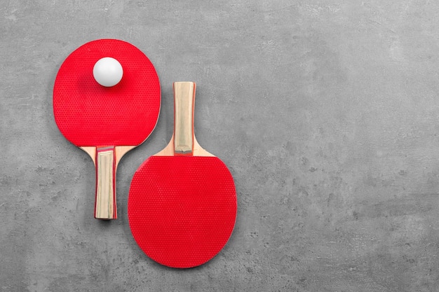 Ping pong rackets and ball on grey background