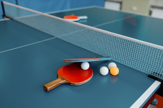 Photo ping pong rackets and balls on game table with net