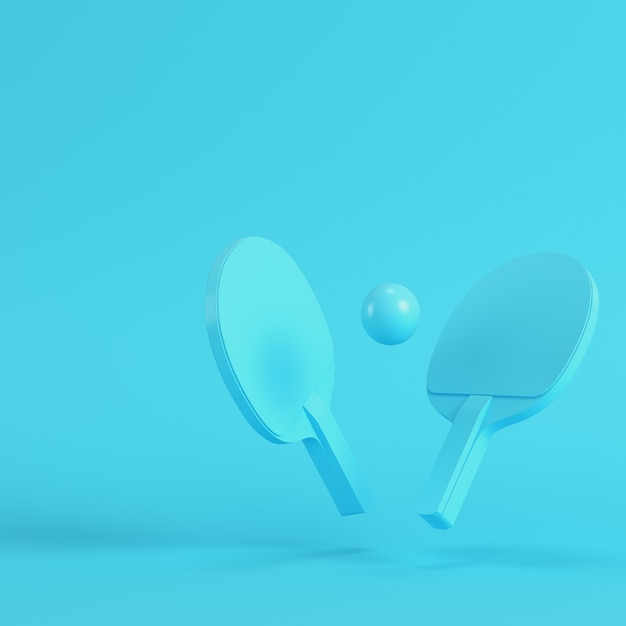 Ping pong rackets with ball on bright blue background in pastel colors. Minimalism concept